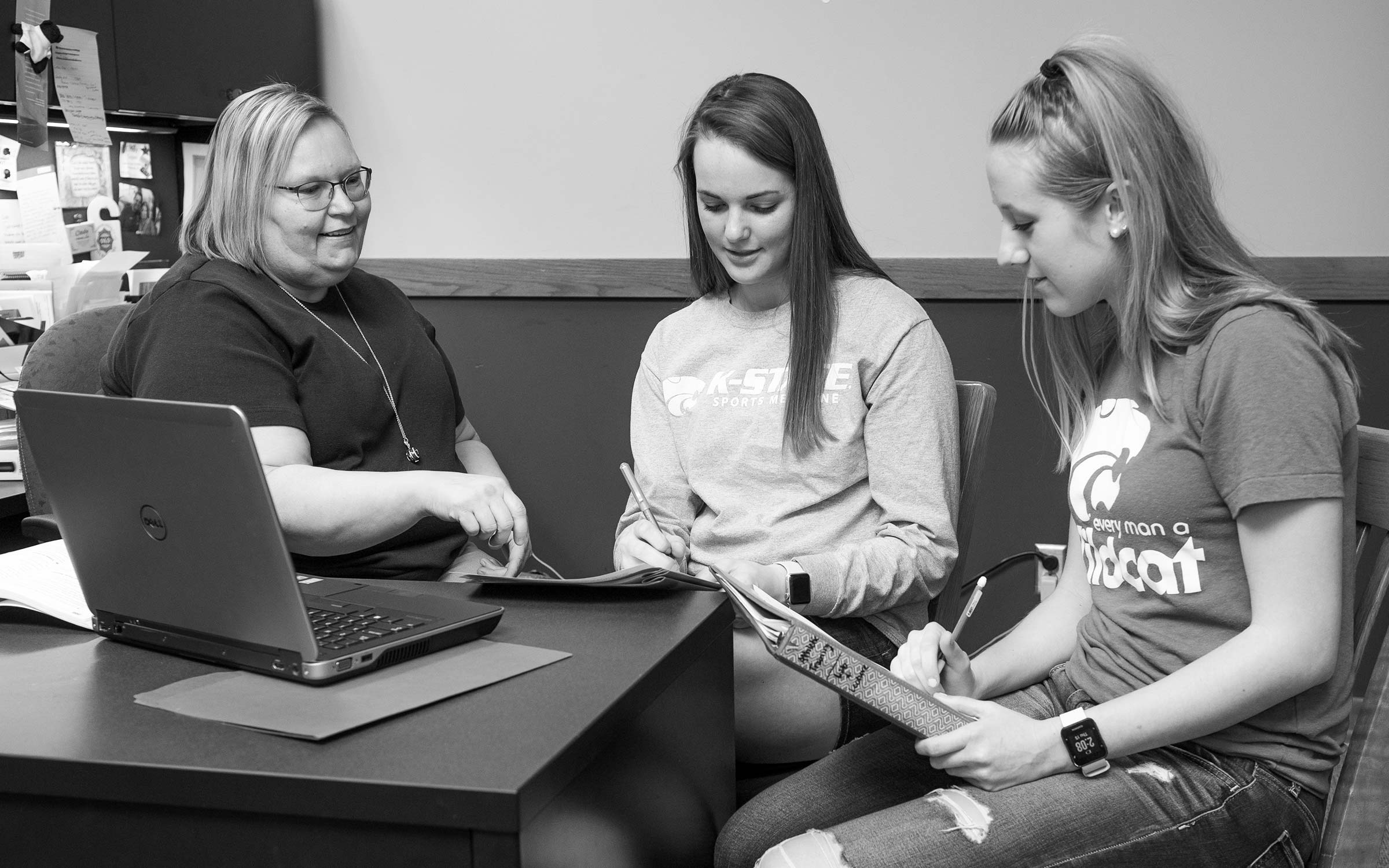 Librarian helping two students.